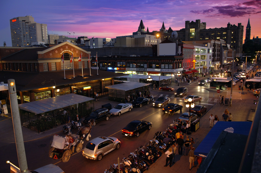 Sunset in the in the Byward Market, busy with a horse-drawn buggy, cars and pedestrians.